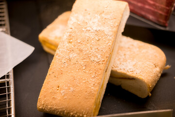 Appetizing panini sandwiches with visible fillings, displayed on a dark surface, likely in a cafe or deli