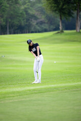 Asian woman professional golfer play golf at golf course with green golf course background, Asian woman golf player swing tee off on the green, Healthy and Lifestyle.