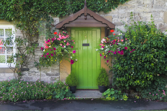 Beautiful country cottage with a lime green door and lovely hanging baskets either side a very welcoming sight for callers and visitors.