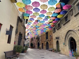 Colorful Umbrellas Floating Over Quaint Street in Barcelona