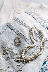 Elegant pearl and silver charm necklaces on clothes and jeans.  .Fashionable layered silver necklaces with pendants and with silver heart pendant