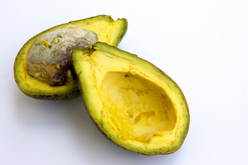 A sliced avocado, with its seed and yellow flesh, isolated on white background.