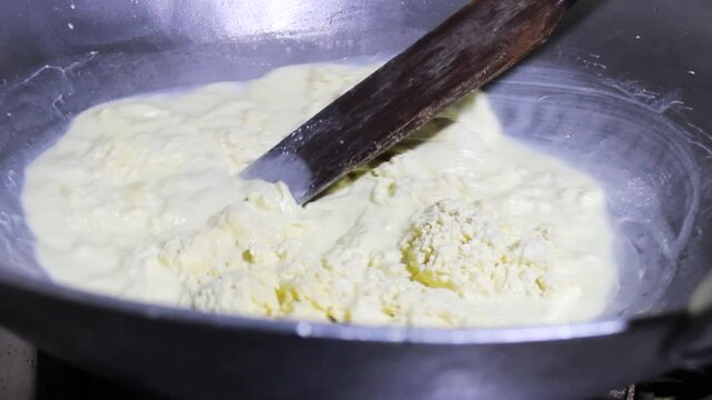Hands of an unrecognizable person mixing a substance in a pot to prepare Quesillo Yaguare&ntilde;o inside a kitchen in Yaguar&aacute;, Huila, Colombia. Colombian food concept