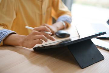 Male web designer drawing with graphic tablet at table in office.