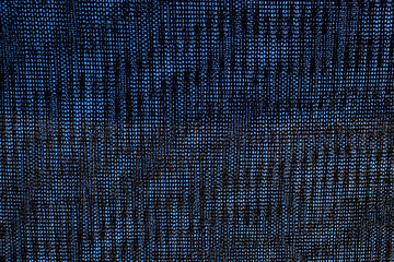 Close-up of black shading mesh against a blue sky. Commonly used in agriculture to protect crops from sunlight