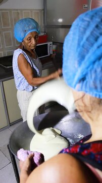Two colombian women mixing a milk drink in a pot to prepare the typical Quesillo Yaguare&ntilde;o in Yaguar&aacute;, Huila, Colombia. Artisanal food concept