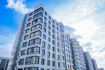 The concept of a multi-storey lady, a residential complex, an urban living environment. A view from below of the corner of the house of the residential complex, behind which you can see another house