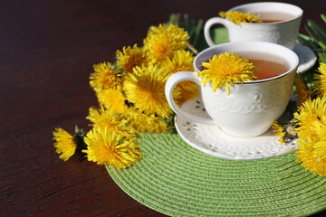 Dandelion tea with a fresh yellow flower inside a cup. Vitamin drink. Dandelion herbal tea for health.