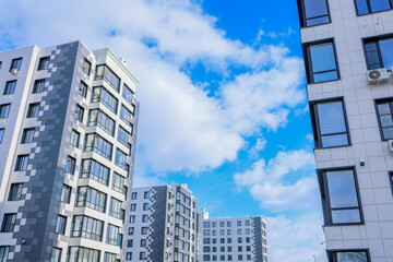 Obraz premium The concept of a multi-storey lady, a residential complex. A view from below of the houses of the residential complex, which stand one after another, on the side there is also a close-up of the house
