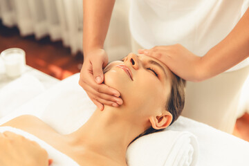Caucasian woman enjoying relaxing anti-stress head massage and pampering facial beauty skin recreation leisure in dayspa modern light ambient at luxury resort or hotel spa salon. Quiescent