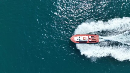 Aerial drone cinematic tracking video of red pilot boat cruising in high speed in Mediterranean deep blue sea offering navigational aid to ships