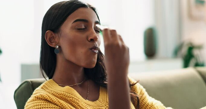 Calm woman, relax and eating chocolate on sofa for sweet snack, dessert or candy at home. Face of happy and young female person with smile, bite and enjoying cocoa delight in living room at house