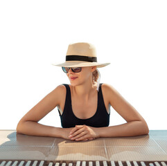 Girl in hat is in pool, leaning on side. Young woman with glasses and hat on vacation is relaxing on edge of pool on sunny day. Portrait of woman in pool looking at camera. Sitting on edge of pool