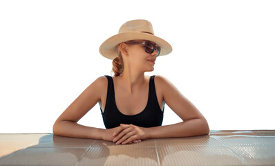 Girl in hat is in pool, leaning on side. Young woman with glasses and hat on vacation is relaxing on edge of pool on sunny day. Portrait of woman in pool looking at camera. Sitting on edge of pool