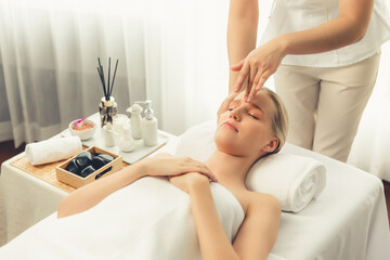 Fototapeta premium Caucasian woman enjoying relaxing anti-stress head massage and pampering facial beauty skin recreation leisure in dayspa modern light ambient at luxury resort or hotel spa salon. Quiescent