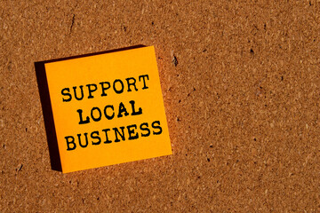 Support local business message written on orange paper on brown background. Conceptual support...