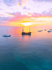 Aerial view of colorful sunrise over ocean in Punta Cana. Boats anchored in calm waters, surrounded...