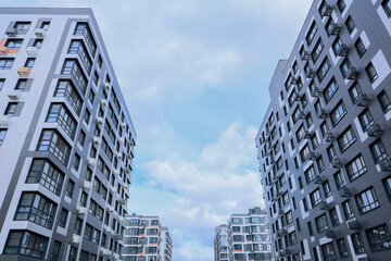 Fototapeta premium Contemporary apartment buildings beautifully framed by a serene sky that features soft, fluffy clouds above them