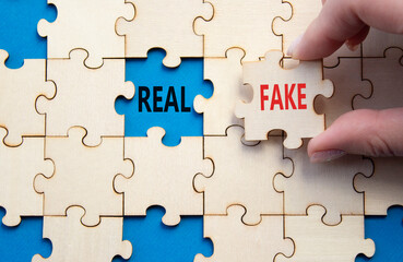 Real or Fake symbol. Concept word Real or Fake on wooden blocks. Businessman hand. Beautiful blue...