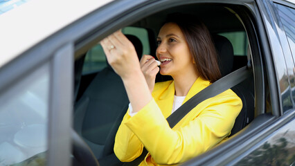 Businesswoman applying lipstick while sitting in car
