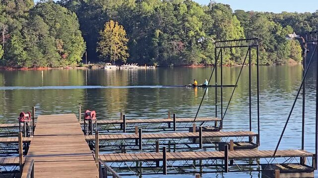 footage of people rowing a boat in a gorgeous landscape with rippling water and lush green trees at Lake Lanier Olympic Park in Gainesville Georgia USA