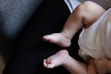 closeup of newborn feet sticking out of tiny white onesie