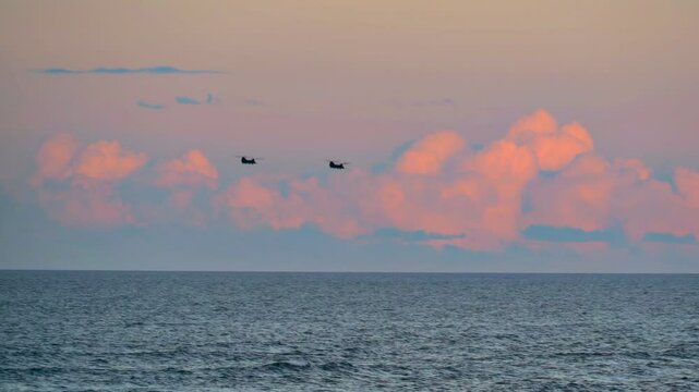 The Boeing MH-47G is a special operations variant of the CH-47 Chinook helicopter. This clip features 2 of the special helicopters flying over the Atlantic Ocean with fluffy pink clouds on the horizon