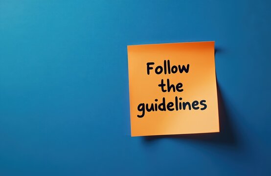 Orange sticker note with Follow the guidelines message, blue background. Concept of rules compliance, instruction, regulatory process, business, legal, education. Copy space for text.