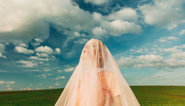 Dreamy outdoor portrait of a woman under sheer fabric