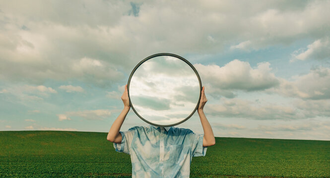 Surreal portrait with round mirror reflecting cloudy sky