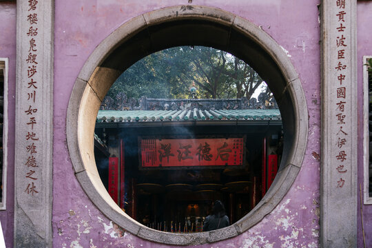 Worship scene viewed through the circular gateway of a Chinese temple in Macau