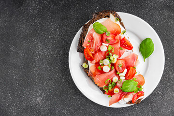 Bruschetta ham, tomato, greens dish fresh delicious gourmet food background on the table rustic food top view copy space