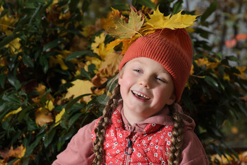 A girl has decorated herself with yellow maple leaves.