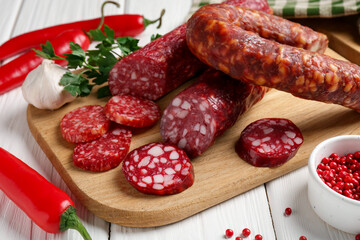 Different smoked sausages and spices on white wooden table, closeup