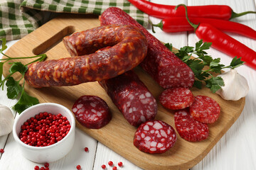 Different smoked sausages and spices on white wooden table, closeup