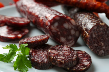 Different smoked sausages and parsley on plate, closeup