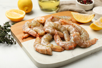 Fresh raw shrimps, spices and lemons on white table, closeup