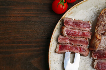 Pieces of delicious beef meat and tomato on wooden table, top view. Space for text
