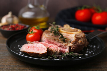 Pieces of delicious beef meat, spices and tomatoes on wooden table, closeup