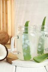 Refreshing drink with coconut and aloe on white wooden table