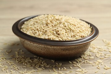 Brown rice in bowl on wooden table, closeup