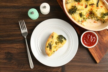 Tasty vegetable casserole served with sauce and spices on wooden table, flat lay