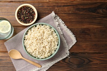 Delicious brown rice served on wooden table, flat lay. Space for text