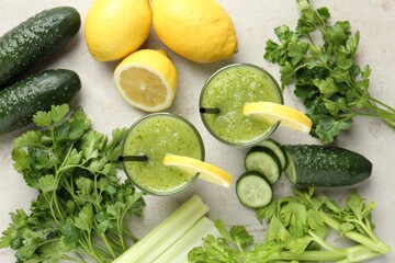 Healthy parsley smoothie in glasses, leaves, lemon and cucumber on light textured table, flat lay