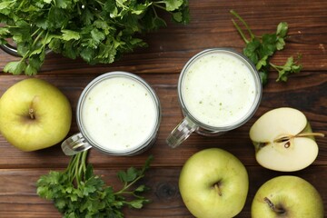 Healthy parsley drink in glasses, leaves and apples on wooden table, flat lay