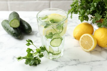 Healthy drink with parsley, cucumbers and lemons on white marble table, closeup