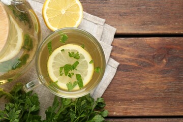 Healthy parsley tea with lemon slices on wooden table, flat lay and space for text. Detox drink