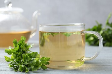 Healthy parsley tea on grey wooden table, closeup. Detox drink