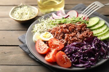 Tasty salad with brown rice served on wooden table, closeup