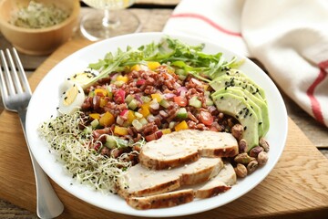 Tasty salad with brown rice served on wooden table, closeup